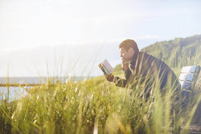 Homme lisant un livre dans la nature.