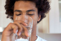 Un homme de race noire buvant un verre d'eau. L'eau contaminée à l'APFO menacerait la santé de six millions d'Américains.  L'eau contaminée à l'APFO menacerait la santé de six millions d'Américains.