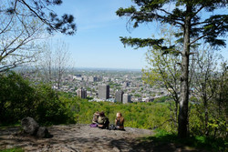 DEux personnes assises au sommet du mont Royel avec vue sur la ville de Montréal.