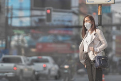 Femme avec masque attendant de traverser la rue en ville.